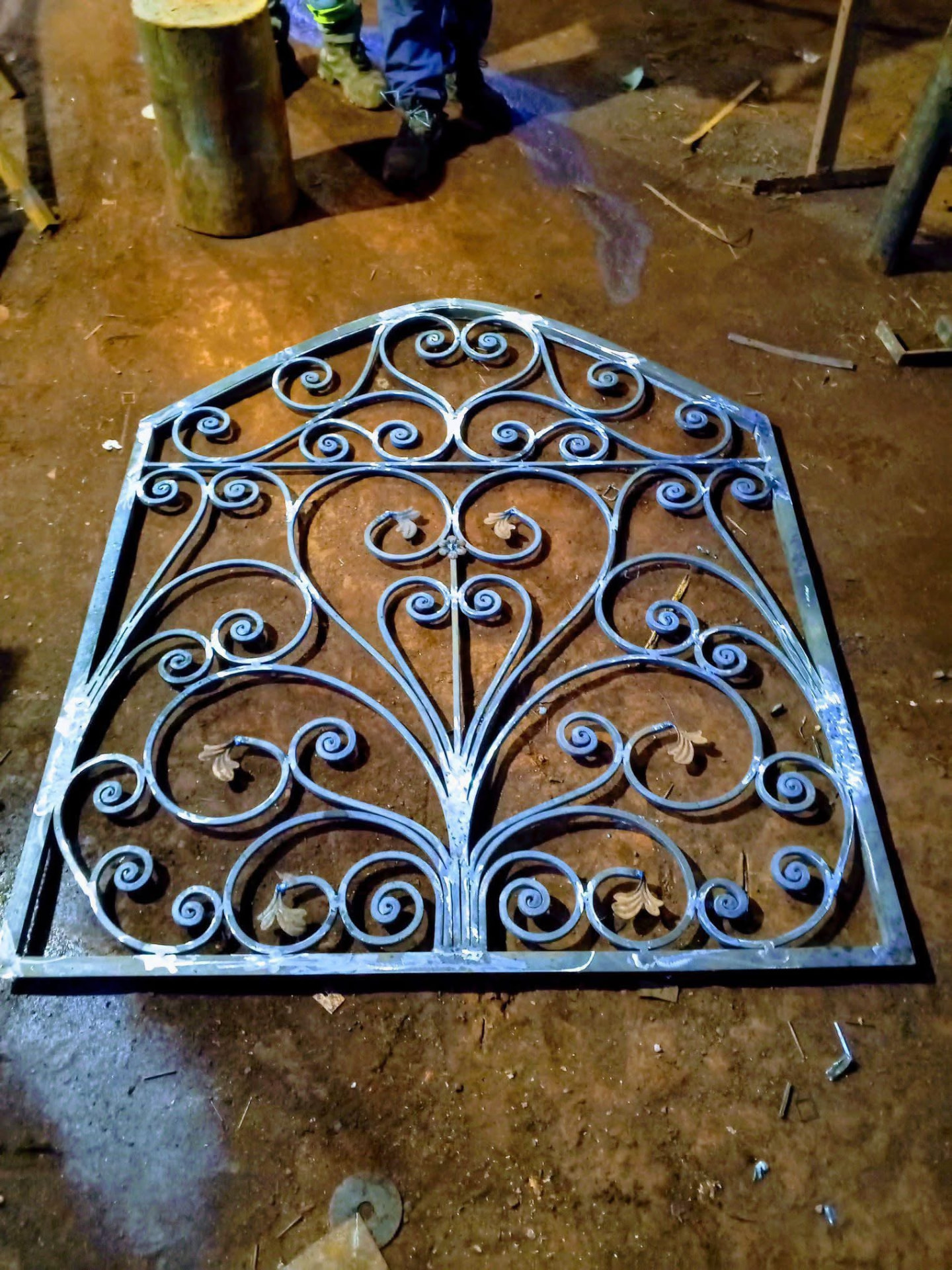 Arched iron scrollwork panel freshly welded on the shop floor